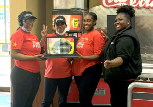 Hardee's employees smiling with their title belt. They won the store of month competition!